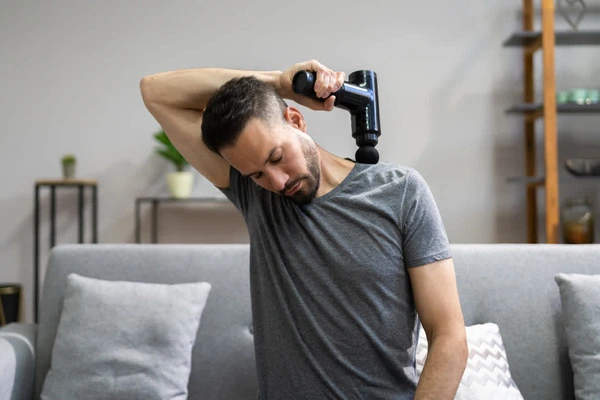man using gun massager on neck